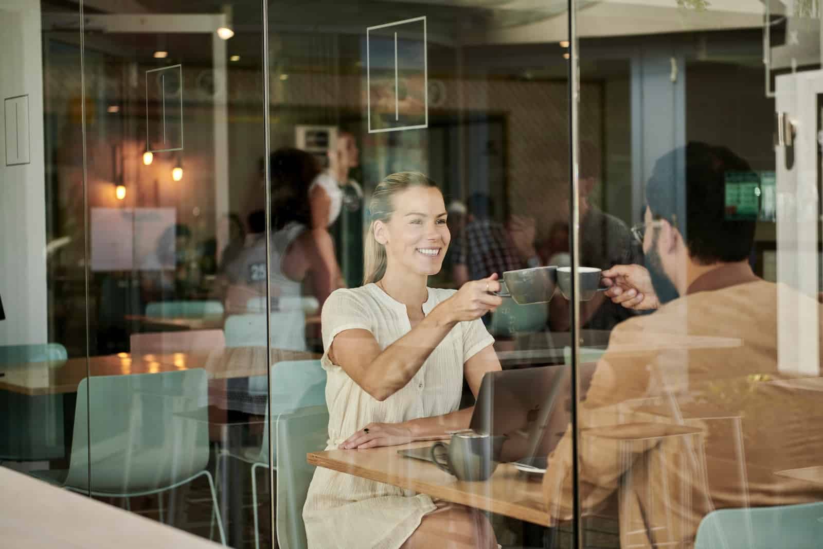 woman in white shirt sitting at coffee shop with man in brown jacket