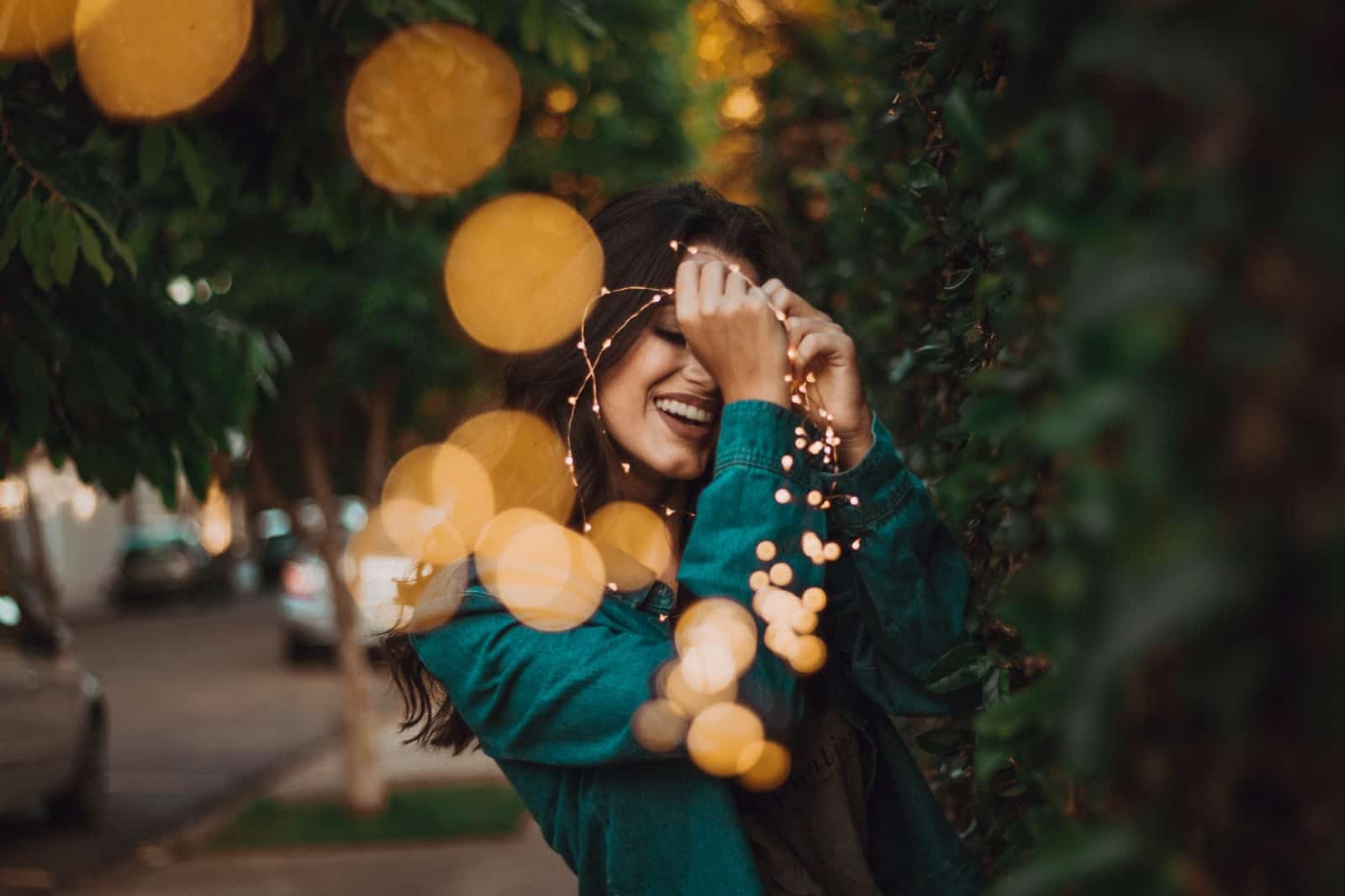 woman standing in front of green leafed plants with light bokeh