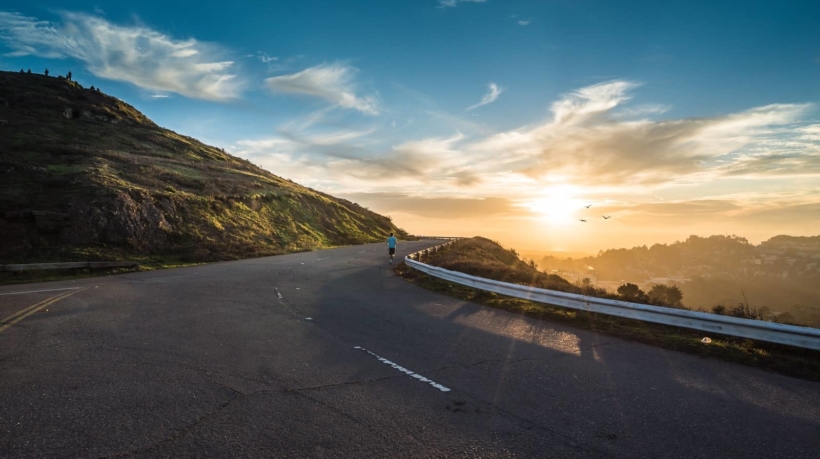 person running on road street cliff during golden hour